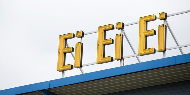 Der Schriftzug "Ei, Ei, Ei" in gelben Neonbuchstaben auf einem Vordach
