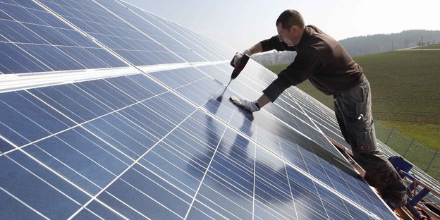 Mann montiert Solarzellen auf ein Dach