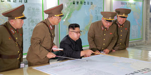 Kim Jong Un und vier Uniformierte schauen auf eine Karte
