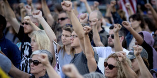 Mehrere Menschen strecken die Faust in die Höhe.