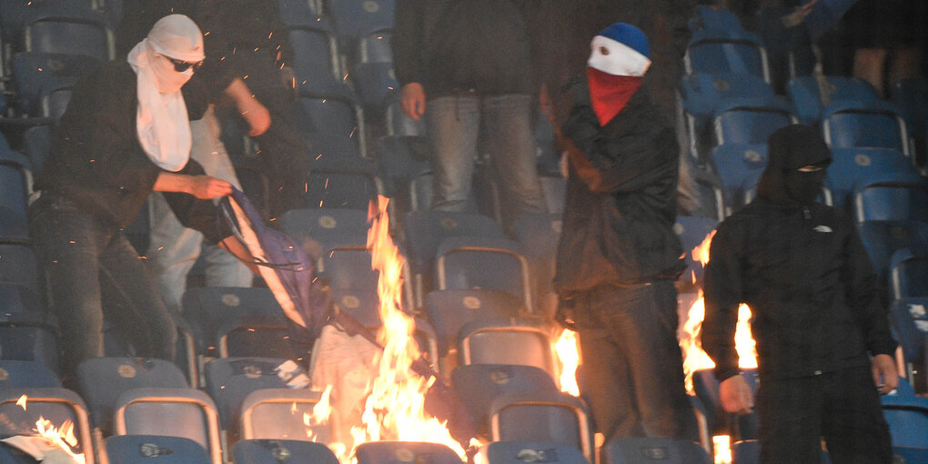 Maskierte entfachen ein Feuer zwischen den Zuschauersitzen