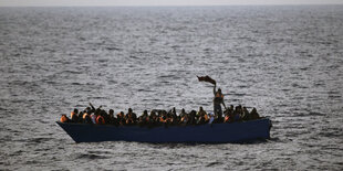 Ein Boot auf hoher See, darin viele Menschen mit Schwimmwesten