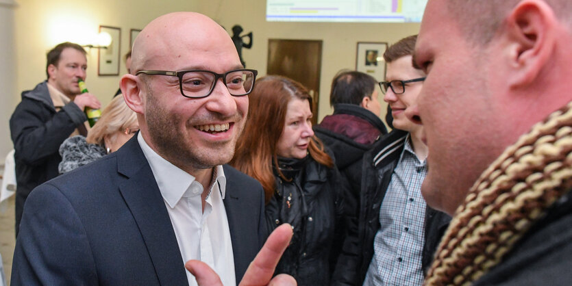 René Wilke spricht mit jemanden, im Hintergrund stehen mehrere Menschen