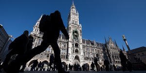 Das Rathaus am Münchner Marienplatz im Sonneschein, davor Passanten im Schatten