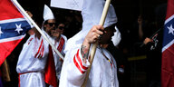 Zwei Männer mit weißen Kapuzengewändern und der Fahne der Konförderierten