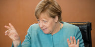 Angela Merkel hebt beide Hände und krallt die Finger