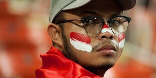 Ein Mann mit Baseball-Kappe und Brille guckt ernst