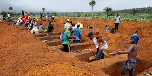 Arbeiter in Freetown heben in roter Erde Gräber aus