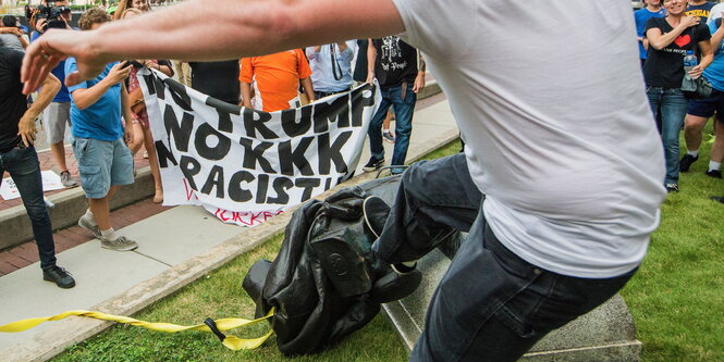 Ein Demonstrant tritt in Durham nach einem am Boden liegenden Denkmal eines konföderierten Soldaten