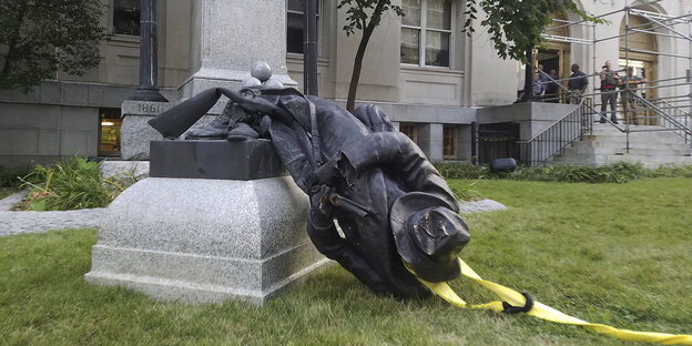 Ein vom Sockel gestürztes Konföderiertendenkmal liegt in Durham am Boden