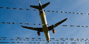 Ein Flugzeug über Stacheldrahtzaun