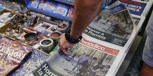 Eine Hand greift nach Zeitungen