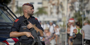 Polizist mit Maschinengewehr steht auf einer Straße