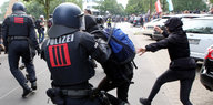 Ein Polizist hält einen Demonstranten am Arm fest und setzt seinen Schlagstock ein