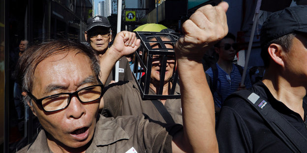 Chinesen in Gefängnisuniformen drängen sich protestierend auf der Straße