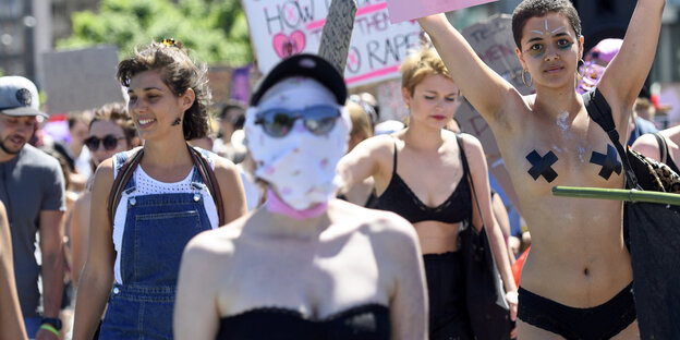 Frauen auf einer Demo, eine hat ihr Gesicht verummt. eine andere ist barbusig