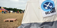 Auf einem Zelt hängt ein Banner mit der Aufschrift „Ende Gelände“, im Hintergrund läuft eine Reihe Menschen durchs Bild