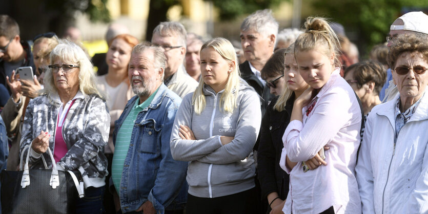 Menschen mit besorgten Gesichtern stehen beisammen