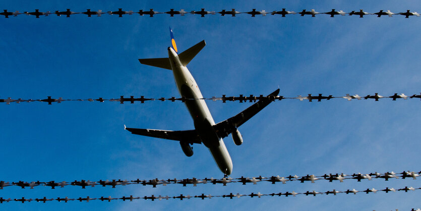 Ein Flugzeug, durch einen Stacheldrahtzaun gesehen