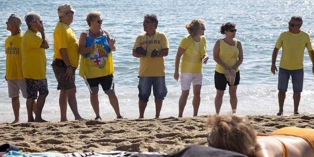 Menschen in gelben T-Shirts stehen in einer Reihe am Strand