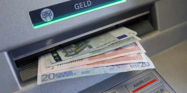 Geldscheine im Ausgabeschitz eines Geldautomaten