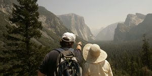Ein Mann und eine Frau stehen nebeneinander. Er zeigt auf eine Bergkette, die sich am Horizont befindet.