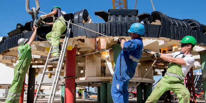 Männer bauen an einem Schneiderad, das für eine Tunnelbohrmaschine gedacht ist