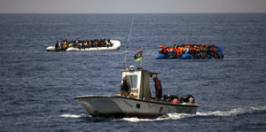 zwei Flüchtlingsboote und ein Schiff im Meer