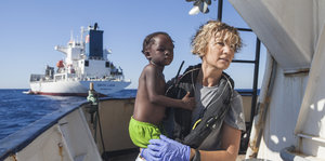 Eine Krankenschwester hält ein Kind auf dem Arm auf einem Schiff