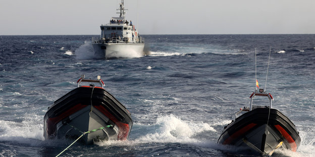 Ein Boot fährt auf dem Meer zwei kleineren Schlauchbooten hinterher