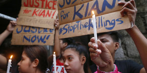 Mädchen und Jungen halten Kerzen und Schilder in die Höhe. Auf den Schildern steht: „Gerechtigkeit für Kian“. Er wurde zuvor erschossen.