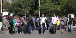 Viele Menschen mit verschiedenen Gepäckstücken auf einer Straße