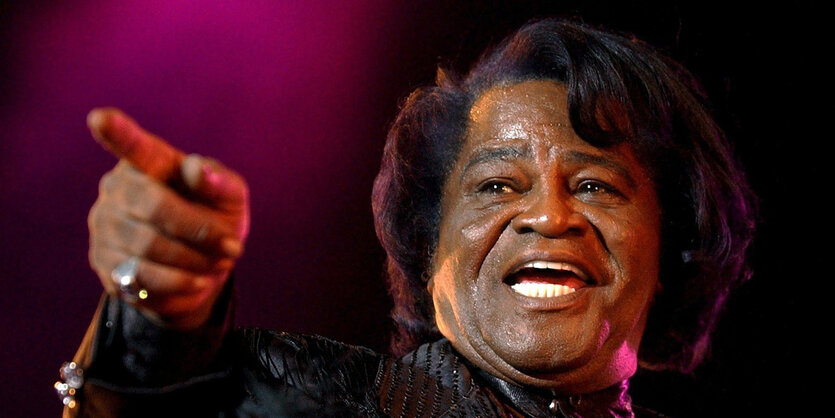 James Brown zeigt mit dem Finger in die Ferne