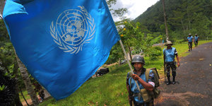 Ein Soldat trägt eine blaue UNO-Flagge