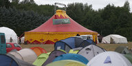 Vor einem Zirkuszelt stehen viele kleine Zelte