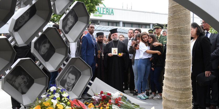 Menschen trauern vor einem Denkmal