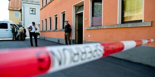 Absperrband vor einem Haus, dahinter ein Polizist