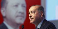 Erdogan steht vor einem überlebensgroßen Bild von Erdogan und spricht in ein Mikro