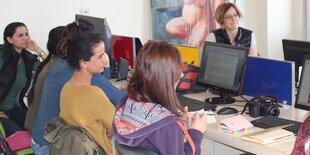 Frauen sitzen an einem Tisch, auf dem Computer stehen