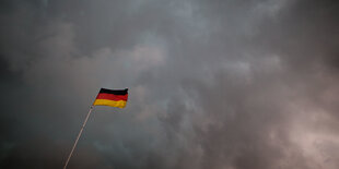 Eine Deutschlandfahne vor dunklen Wolken