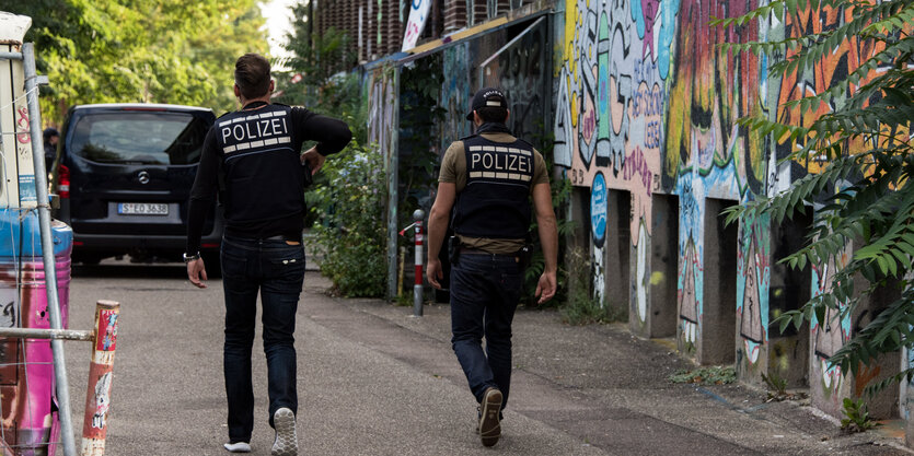 Zwei Polizisten vor einer Wand mit Graffiti