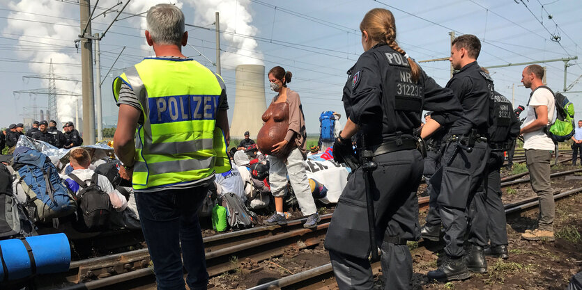 Menschen sitzen auf Bahngleisen