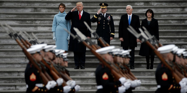 Soldaten in Paradeuniform marschieren an Trump und vier weiteren personen vorbei