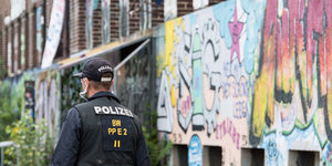 Ein Polizist vor einer mit Grafitti besprühten Wand