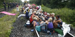 Viele Menschen sitzen auf einem Bahngleis