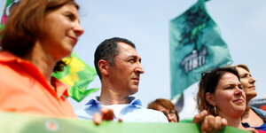 Özdemir ist in einer Menschenmenge zu sehen. Er hält ein grünes Banner.
