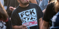 Ein Mann trägt ein T-Shirt mit der Aufschrift „FCK NZS“