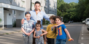 eine Familie posiert auf der Straße vor einem Haus für die Kamera
