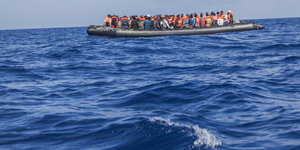 Ein Boot mit vielen Menschen darauf schwimmt im Meer