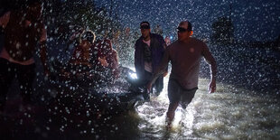 Zwei Männer ziehen in heftigem Regen ein Boot